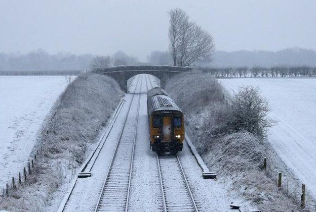 Train passes through snow covered fields near Manchester