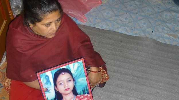 Dewi Sunuwar holds a picture of her daughter who was tortured and killed