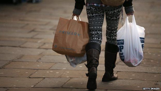 A woman carries several shopping bags from discount shops along Lewisham high street in December 2012