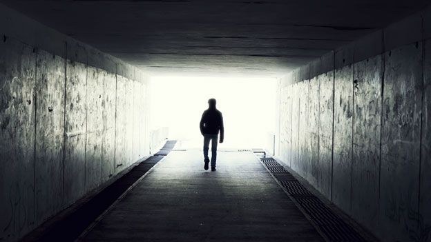 Man in tunnel walking towards light