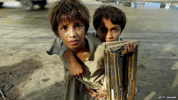 An abandoned boy carries his disabled brother on his back in Karachi in 2003