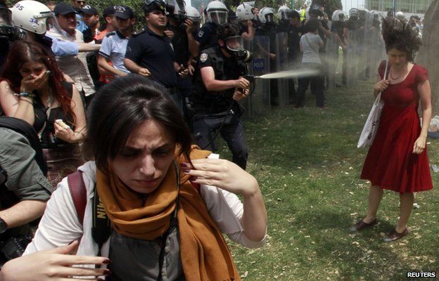 A Turkish riot policeman uses tear gas against Ceyda Sungur in Taksim Square
