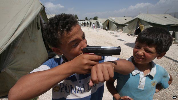 A boy plays with a gun at a refugee camp in Jordan