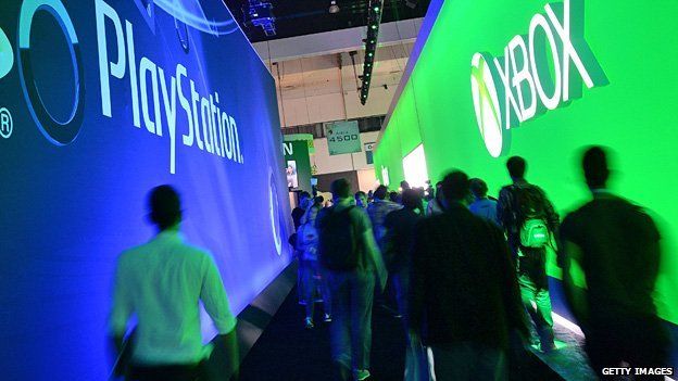 Attendees walk between signs for Sony PlayStation and Microsoft XBox on the first day of the Electronic Entertainment Expo (E3) in Los Angeles