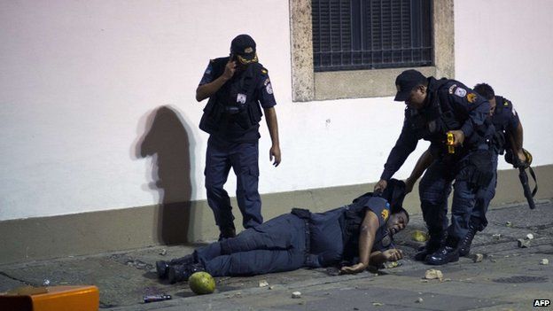 An policeman is dragged by his colleagues after being injured in Rio on 17 June 2013