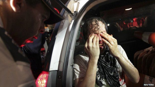 An injured protester rubs his eyes after being arrested in Brasilia on 17 June 2013