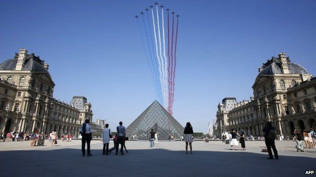 Nine jets from the French Air Force Patrouille de France releasing trails of red, white and blue smoke over the Pyramid du Louvre during the Bastille Day parade, 14 July 2013