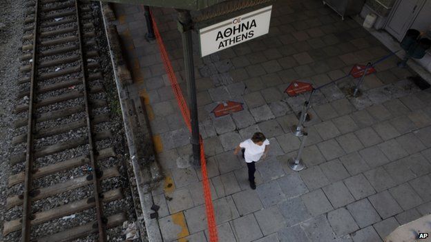 Cleaning worker walks in empty train station in Athens on 16 July 2013