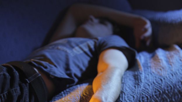 Young man lying on sofa in dark room