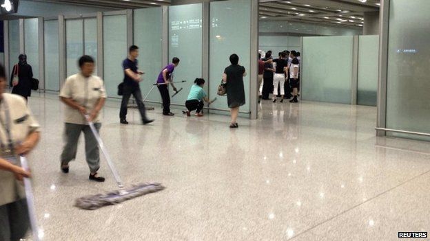 Airport staff clean the floor and glasses at the arrival gate B.