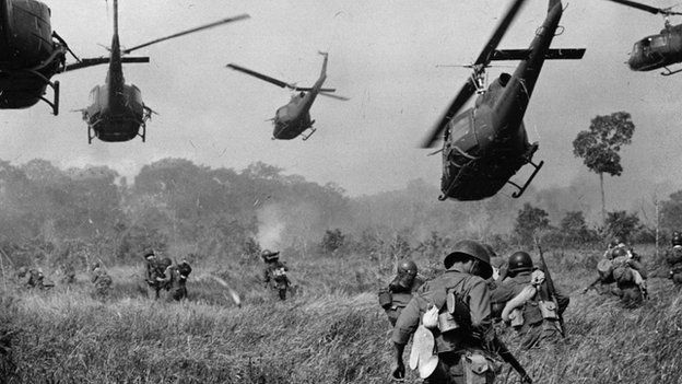 Hovering US Army helicopters pour machine gun fire into the tree line to cover the advance of ground troops