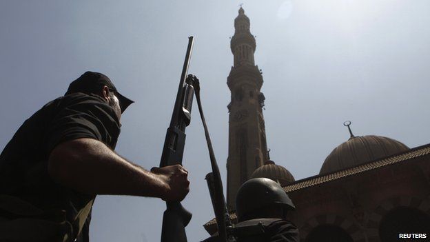Armed Egyptian policeman moves into position in front of al-Fath mosque on Ramses Square in Cairo (17 August 2013)