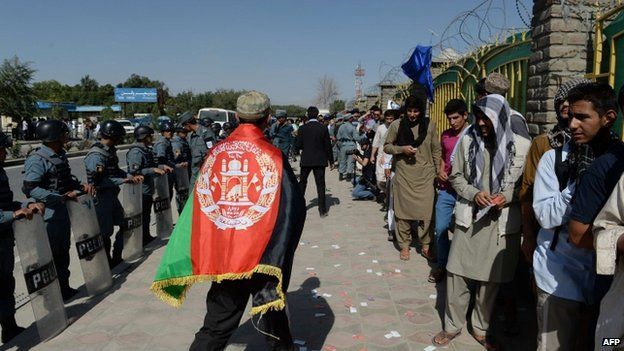 An Afghan football fan walks past fellow supporters queuing to watch their team play against Pakistan