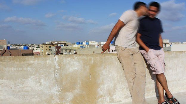 Two men kissing on rooftop