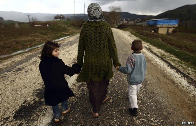 A female refugee holds her children's hands