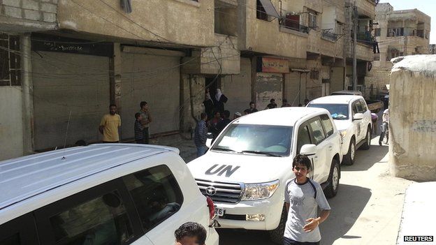 Residents gather around a convoy of UN vehicles carrying a team of UN chemical weapons experts at one of the sites of an alleged poison gas attack in the Damascus suburb of Muadhamiya on 26 August 2013