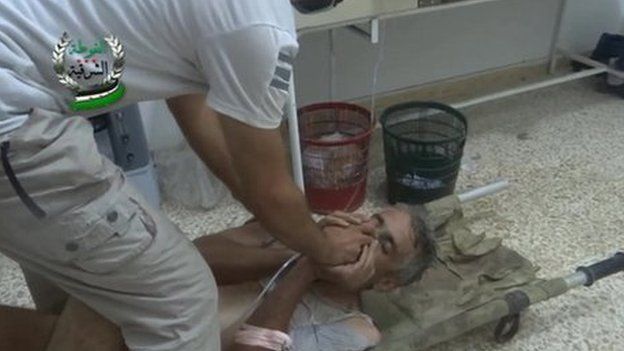 Alleged victim of chemical weapons attack covers his face as he is given an oxygen mask to help him breathe on 21 August 2013