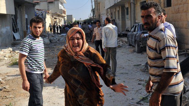 A Syrian woman runs through the debris after an air strike