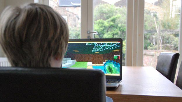 Boy plays Minecraft at kitchen table