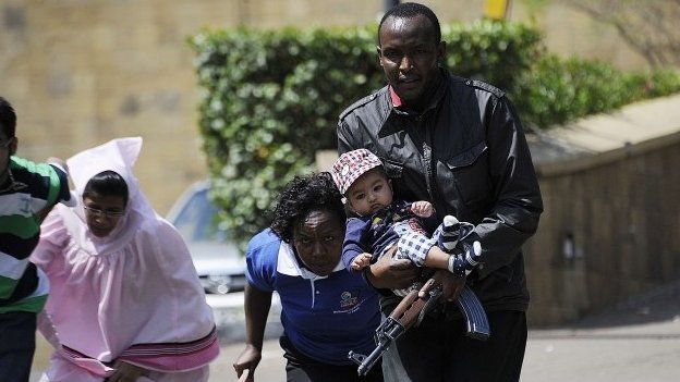 A policeman carries a baby to safety after masked gunmen stormed an upmarket mall on September 21, 2013 in Nairobi.