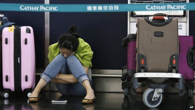 A passenger waits for flights to resume while sitting an airline counter at Hong Kong's international airport after Typhoon Usagi slammed into southern China, Monday, 23 September 2013