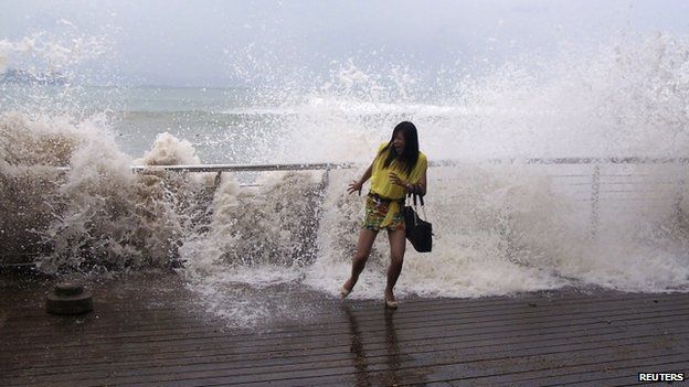A woman reacts as a storm surge past a barrier on the shore as Typhoon Usagi approaches Shenzhen, Guangdong province, 22 September 2013