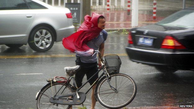 A man pushes his bicycle against the wind as Typhoon Usagi approaches Shantou, Guangdong province, 22 September 2013