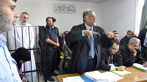 Fathi Ashram (second left) stands inside the Gaza City courtroom during his trial
