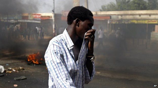 A Sudanese man covers his mouth from heavy smoke after protesters burnt tyres to close the highway to northern cities amid a wave of unrest over the lifting of fuel subsidies by the Sudanese government, in Kadro, 15 miles (24.14 kilometres) north of downtown Khartoum, Wednesday, 25 September, 2013.