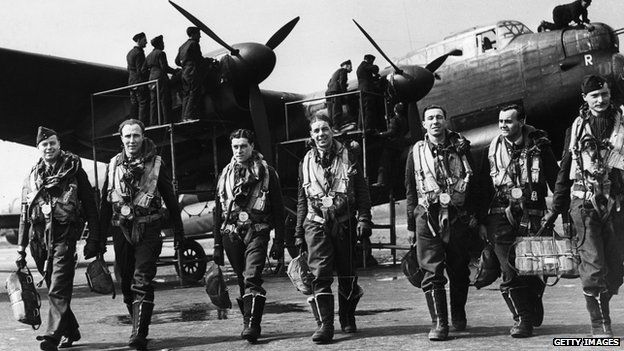 The crew of a Lancaster bomber walk away from their plane after a flight while ground crew check it over, April 1943