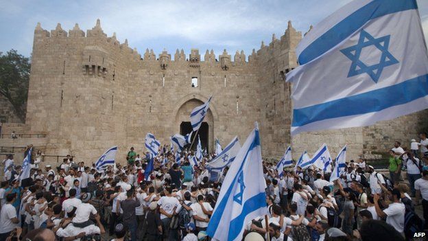Israeli youths hold their national flag as they take part in the "flag march" through Damascus Gate in Jerusalem's old city during celebrations for Jerusalem Day on 8 May, 2013.