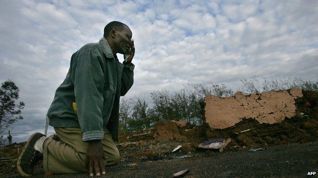 A man who survived an attack on a church where 35 people were burned alive in Kiamba, near the western Kenyan town of Eldoret, weeps as he returns for the first time to the burned out remains of the church on 19 April 2008.