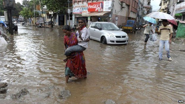 A woman in the Indian city of Hyderabad carries her son across a flooded street