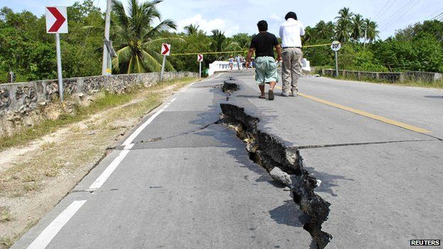 Residents walk along huge cracks in a road after an earthquake struck Bohol province, central Philippines, October 15, 2013.