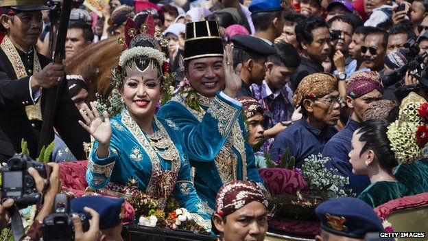 Gusti Kanjeng Ratu Hayu and KPH Notonegoro wave to crowds while on their journey by carriage during the wedding ceremony parade.