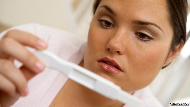 Posed photo of woman looking at pregnancy test