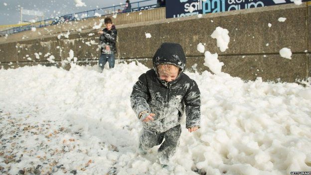 Will Brewer, 4, plays in the foam washed ashore on the Brighton seafront