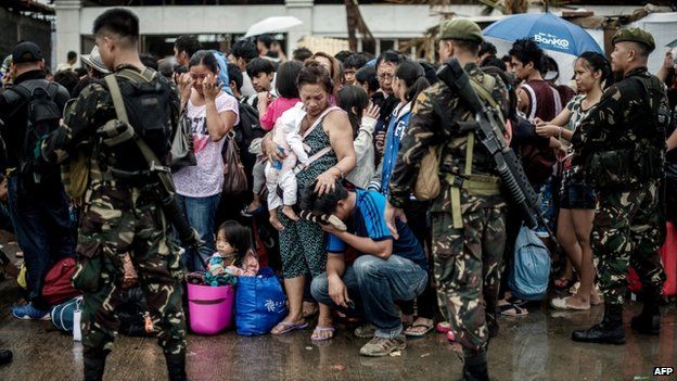 A woman holding a baby comforts a crying relative as a plane leaves the airport during evacuation operations in Tacloban, on the eastern island of Leyte on 12 November 2013