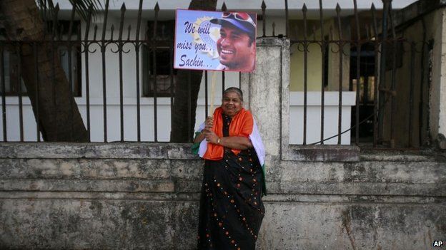 Индийская женщина держит плакат с изображением индийского игрока в крикет Сачин Тендулкар, когда она приезжает посмотреть последний контрольный матч Тендулкара в Мумбаи