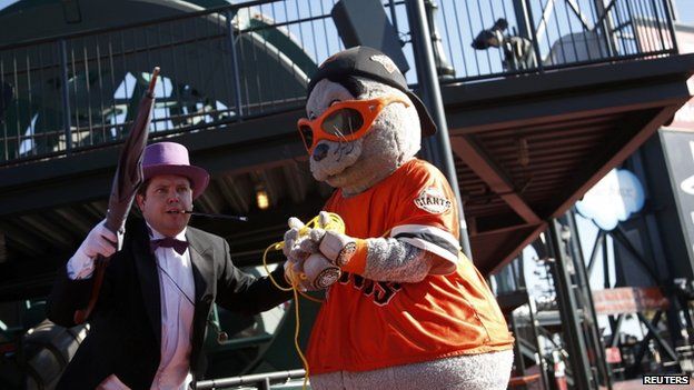 The Penguin holds the San Francisco Giants mascot Lou Seal captive as they wait for the arrival of five-year-old leukemia survivor Miles, aka "Batkid" 15 November 2013