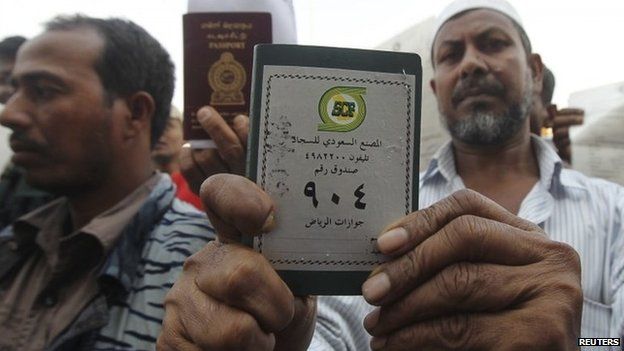 Foreign workers hold up their passports outside a labour office in Riyadh (4 November 2013)