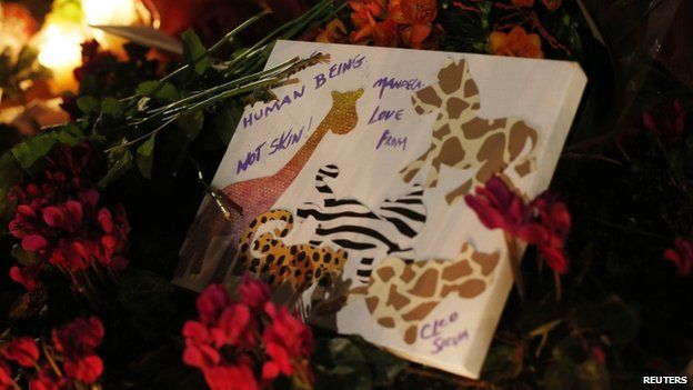 A tribute sits amongst flowers at the base of a statue of Nelson Mandela at Parliament Square in London on 6 December, 2013