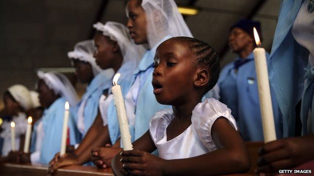 A child holds a candle during Sunday service on a national day of prayer for Nelson Mandela