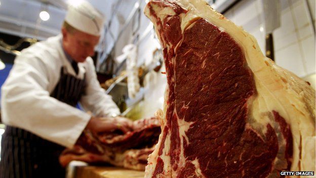 A butcher prepares cuts of Aberdeen Angus beef in his shop August 4, 2003 in London.