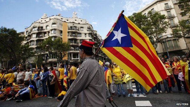 A man with a pro-independence Catalan flag walks in front of people forming a human chain to mark the "Diada de Catalunya" (Catalunya"s National Day) in central Barcelona