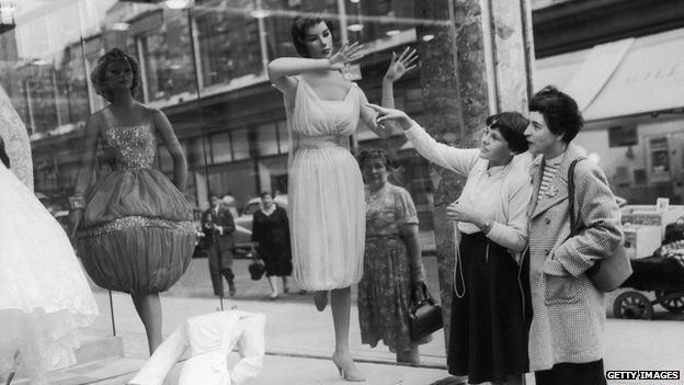 Circa 1950: Passers-by admire the unusual designs in a shop window