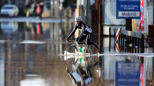 A cyclist riding through deep flood water