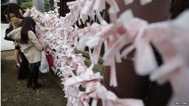 Visitors hang fortune blessing papers at Yasukuni Shrine in Tokyo December 26