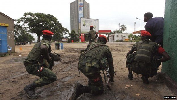 Congolese security officers position themselves as they secure the street near the state television headquarters (C) in the capital Kinshasa, 30 December 2013