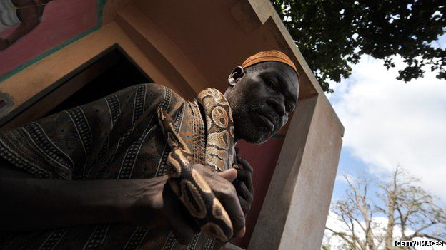 A Benin resident caretaker of the Temple of Pythons holds a python around his neck